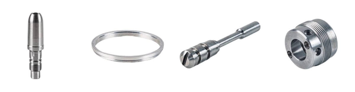 Four expertly CNC-machined metal components are arranged in a row on a white background, showcasing high-precision metalworking and custom parts manufacturing capabilities.